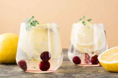 Summer refreshing cold cocktail with lemon and cherry - hard seltzer in glasses on the table