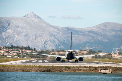 Airplane on sea by mountains against sky