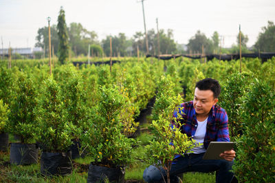 Asian farmer using tablet computer in wheat crop field, concept of modern smart farming 