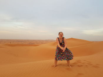 Portrait of cheerful woman standing at desert