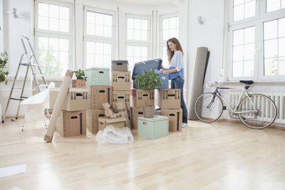 Woman in new apartment unpacking cardboard box