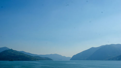 Scenic view of sea and mountains against clear blue sky