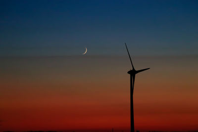 Low angle view of wind turbine against sky during sunset