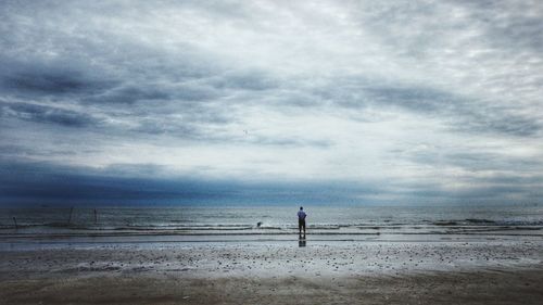 Scenic view of beach against cloudy sky