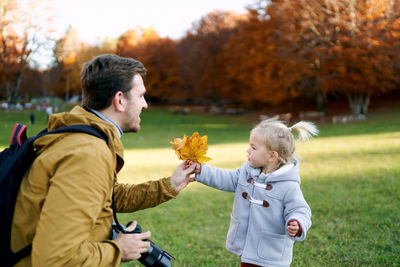 Rear view of boy playing with flowers on field