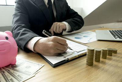 Midsection of businessman writing in graph on table