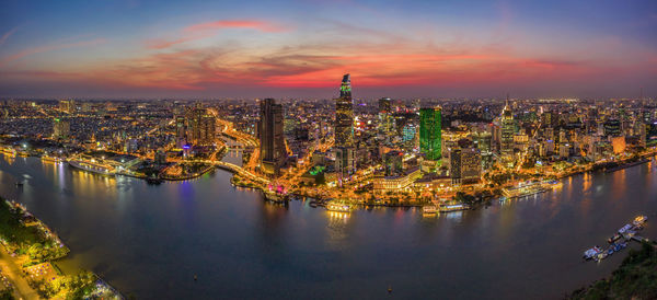 Illuminated buildings in city against sky during sunset