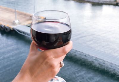 Glass of red wine in womans hand during cruise vacation.