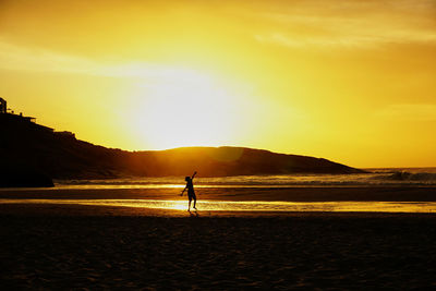 Silhouette man on beach against sky during sunset