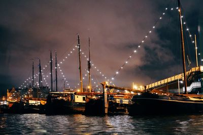 Illuminated bridge over river against sky at night