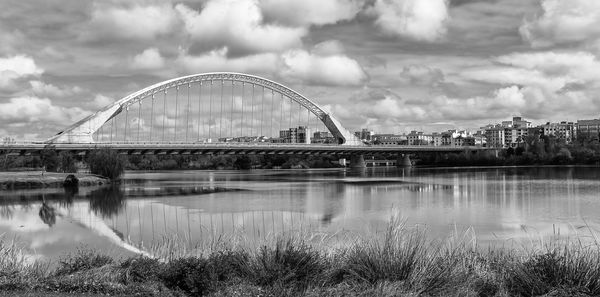 Bridge over river against sky in city