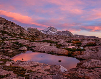 Scenic view of lake by mountains against sky during sunset