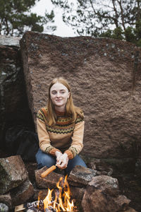 Woman preparing hotdog over campfire