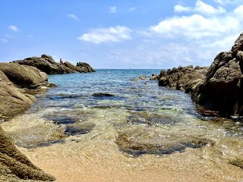 Rock formation on beach against sky