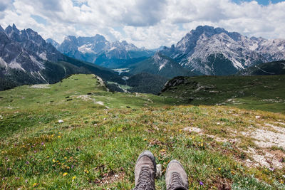 Low section of hiking boots looking at mountains against sky