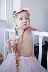 Shirtless girl wearing jewelry in crib