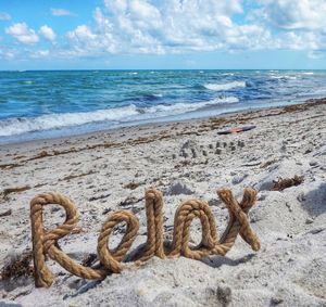 Text on sand at beach against sky