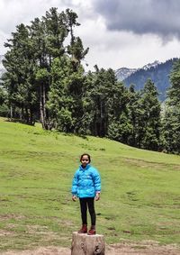 Full length of girl standing on tree stump against trees