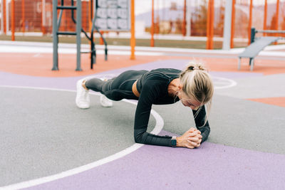 Woman athlete exercising stands in the plank.