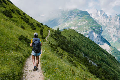 Rear view of man walking on mountain against sky