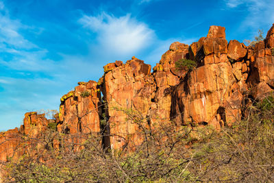 Low angle view of rock formations against cloudy sky