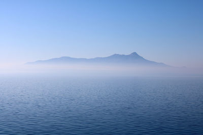 Scenic view of sea and mountains against clear blue sky