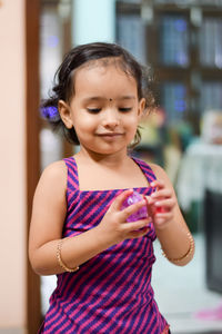 Portrait of cute girl standing against purple