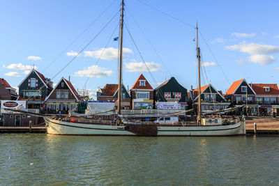 Sailboats moored at harbor against sky in city