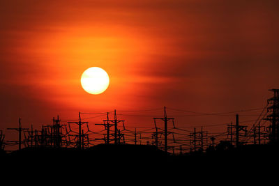 Silhouette electricity pylon against romantic sky at sunset