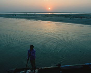 Man fishing in sea against clear sky