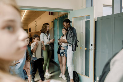 Smiling junior high students standing by door in school corridor