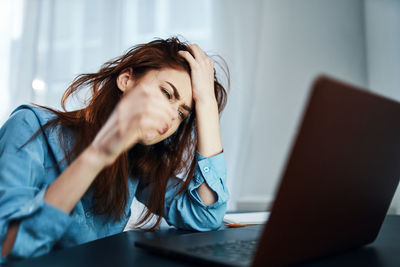 Young woman using mobile phone while sitting on table