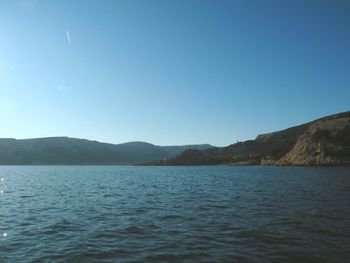 Scenic view of sea and mountains against clear blue sky
