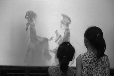 Rear view of women standing against wall