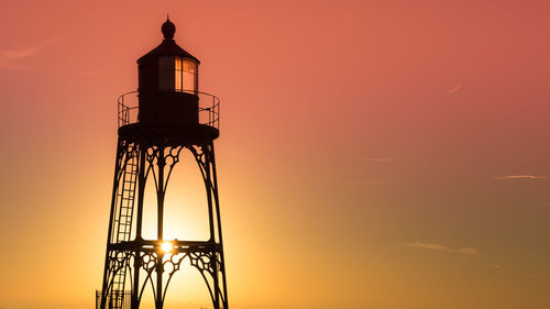 Low angle view of silhouette lookout tower against sky during sunset