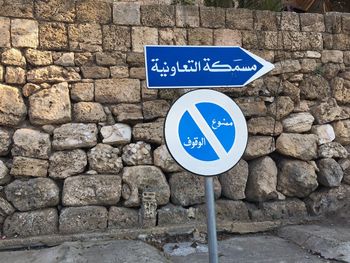 Arabic road sign against stone wall