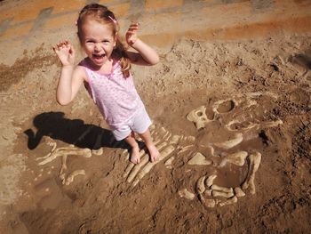 High angle portrait of happy girl standing on sand at beach