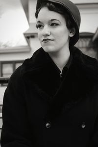 Young woman looking away while standing outdoors