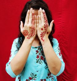 Woman showing henna tattoo against red background