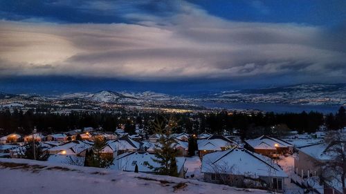 Illuminated houses against sky during winter at night