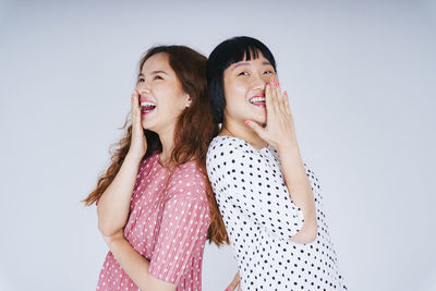 Laughing lesbian couple against gray background