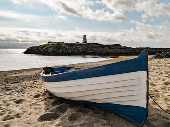 Ship moored on beach against sky