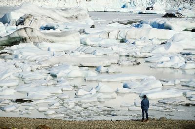 Full length rear view of man looking at icebergs in lagoon