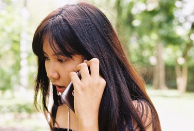 Close-up of young woman talking on smart phone while standing outdoors
