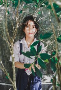 Portrait of young woman standing against plants