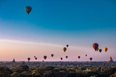 Hot air balloons flying over landscape in sky