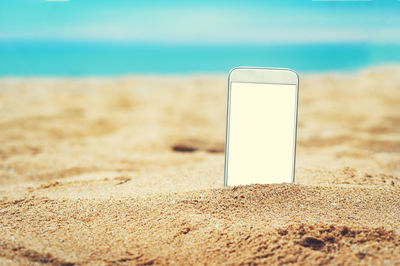 Close-up of smart phone on beach