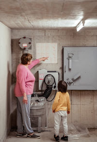 Senior woman with little child in nuclear fallout shelter built in basement of building teaches rule
