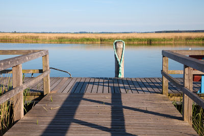 Wooden pier on lake against sky