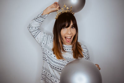 Portrait of young woman holding light bulb against gray background